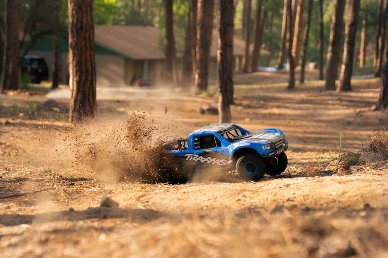 A four-wheel-drive RC truck throwing up dirt on a trail