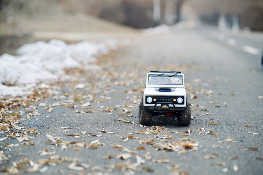 A small RC car on a road scattered with autumn leaves