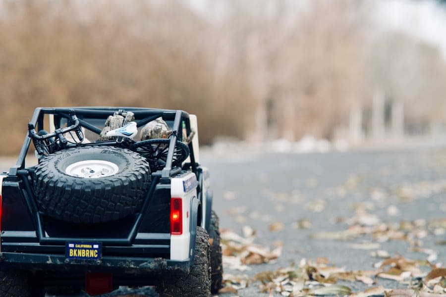 A small scale RC SUV on a leaf-covered forest road
