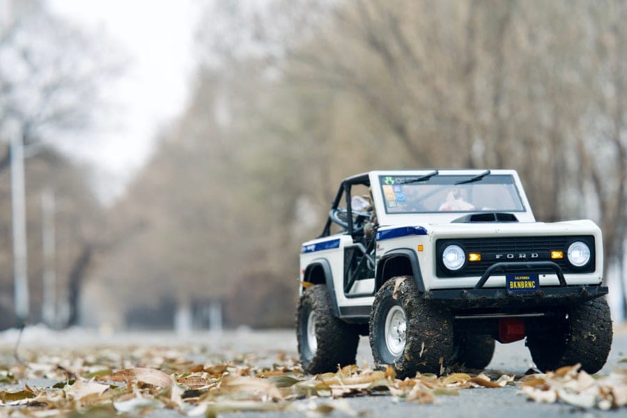 A small off-road RC car on a road covered in autumn leaves