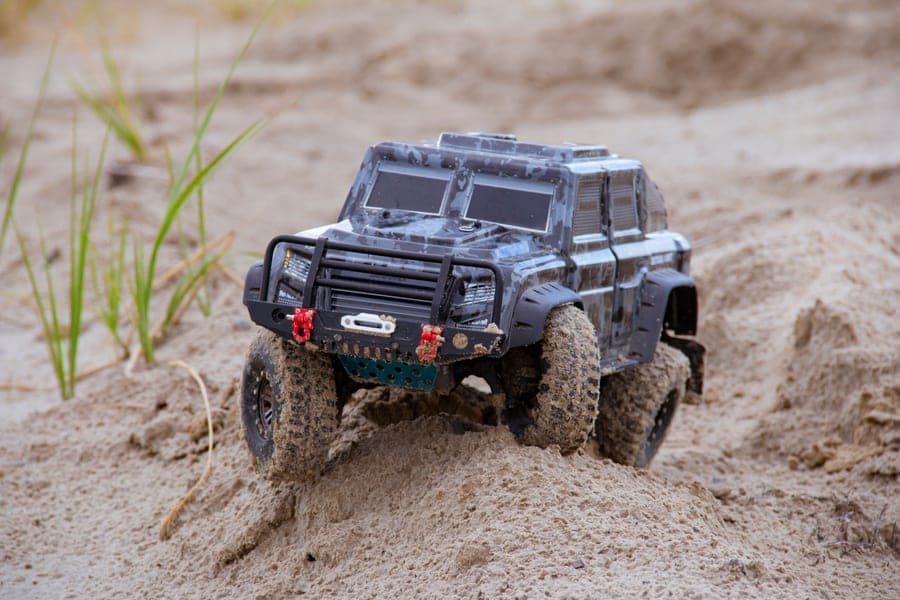 An off-road RC truck driving across sandy ground