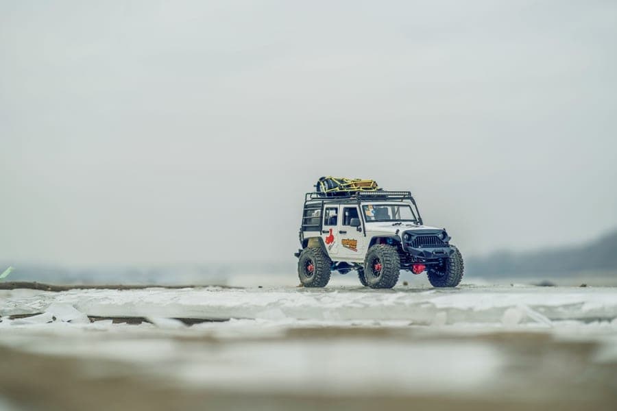 A small four-wheel-drive RC car crossing loose ground