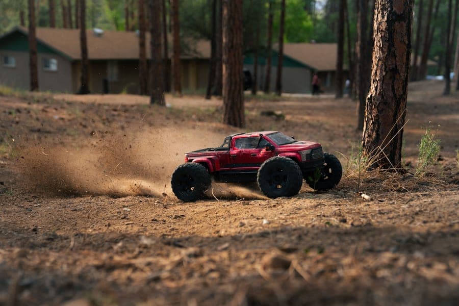 An RC truck sliding on a forest dirt track