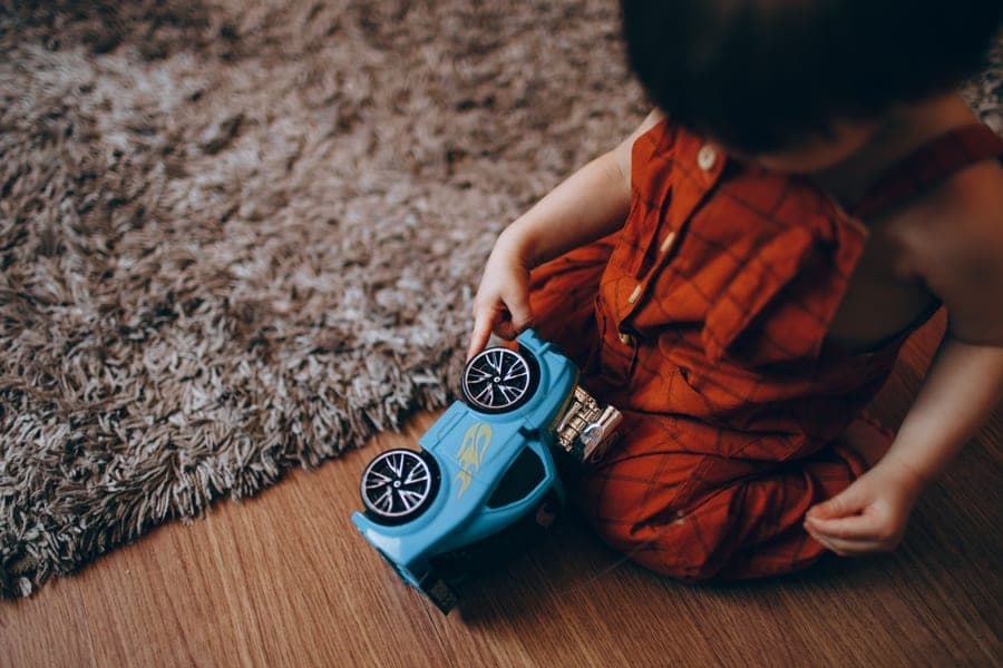 A young child playing with a toy car on the floor indoors